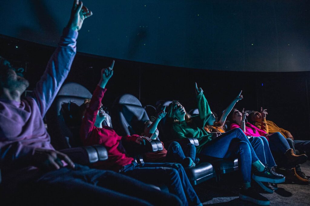Family of all ages in Life science centre's planetarium watching a show about constellations and space.