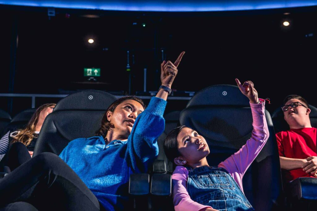 Mother And Daughter Pointing In Planetarium