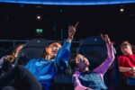 Mother And Daughter Pointing In Planetarium