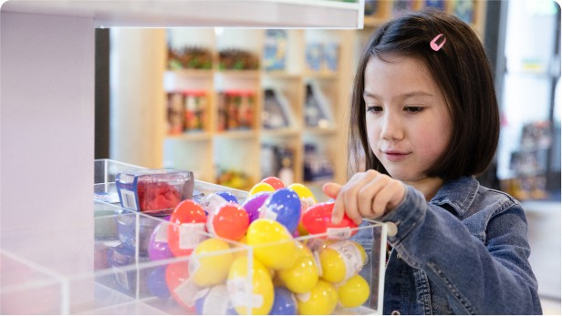Young girl looking at brightly coloured bouncy balls for sale in Life Science Centre's gift shop.