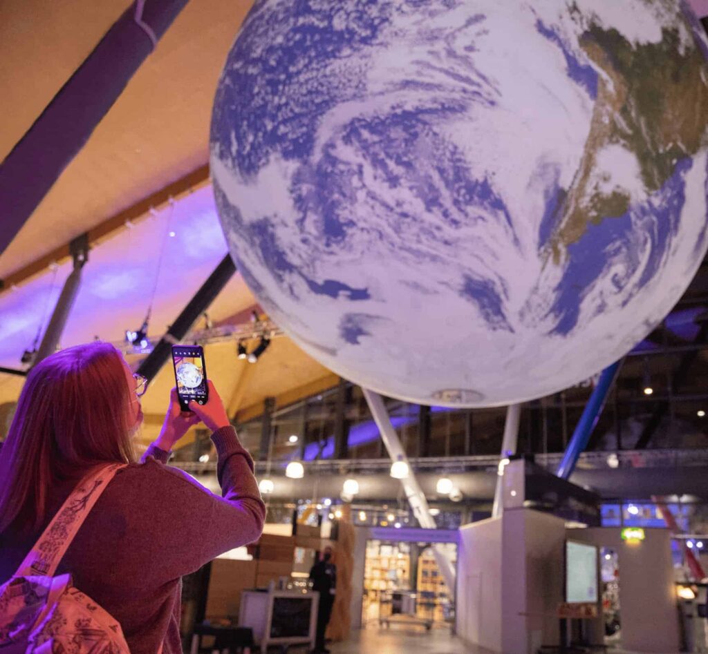 Life Science Centre visitor taking a photo of Gaia, a large replica of Earth, on their mobile phone.