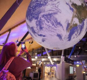 Life Science Centre visitor taking a photo of Gaia, a large replica of Earth, on their mobile phone.