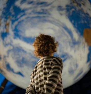 Young boy in stripey shirt, looking up at Gaia, Life Science Centre's Earth replica.