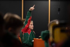 Boy with hand raised during Life Science Centre electricity workshop.