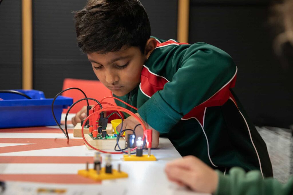 Male student operating electrical circuit board during Life Science Centre education workshop.