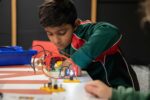 Male student operating electrical circuit board during Life Science Centre education workshop.