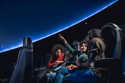 Family visiting Life Science Centre are in the planetarium, looking up at the show.