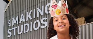 Young girl wearing a homemade party crown in front of Life Science Centre's Making Studios.