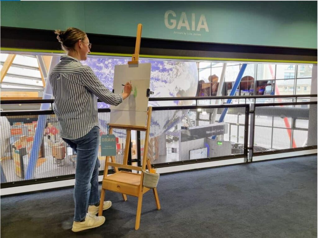 Older student using an easel to draw Planet Earth inside the science centre.