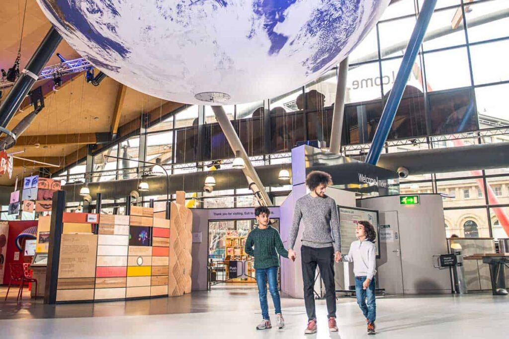 Family entering the science centre underneath Gaia, a large replica of Earth.