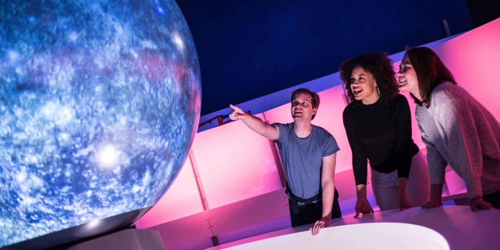 Young adults watching an immersive show on Life Science Centre's Sphere in Space Zone.