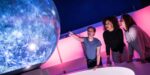 Young adults watching an immersive show on Life Science Centre's Sphere in Space Zone.