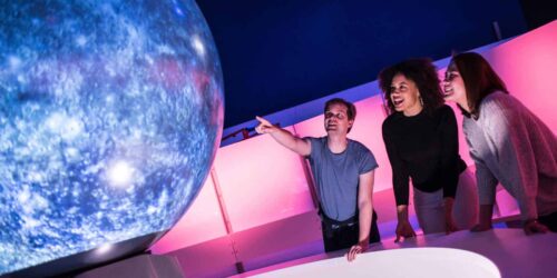 Young adults watching an immersive show on Life Science Centre's Sphere in Space Zone.