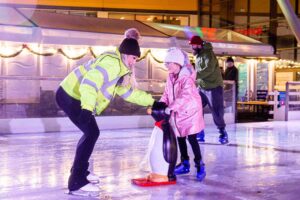 Host assists school student on Life Science Centre's open-air ice rink.