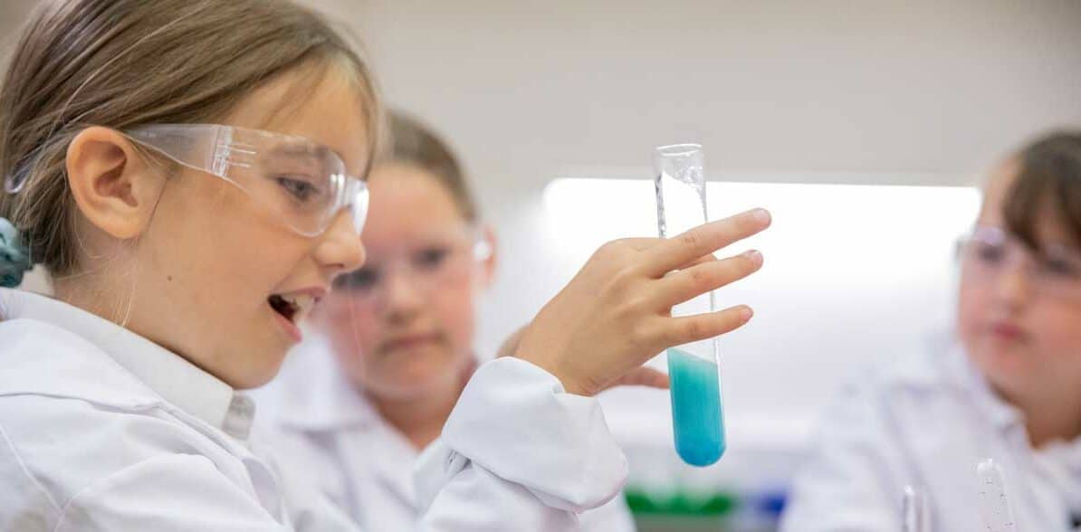 Student looking at test tube whilst completing a practical experiment at an education workshop.