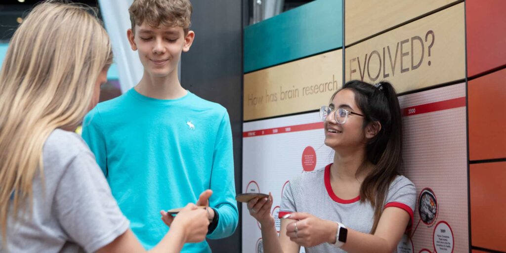 Three teenagers enjoying hands-on fun inside Life Science Centre's Brain Zone.