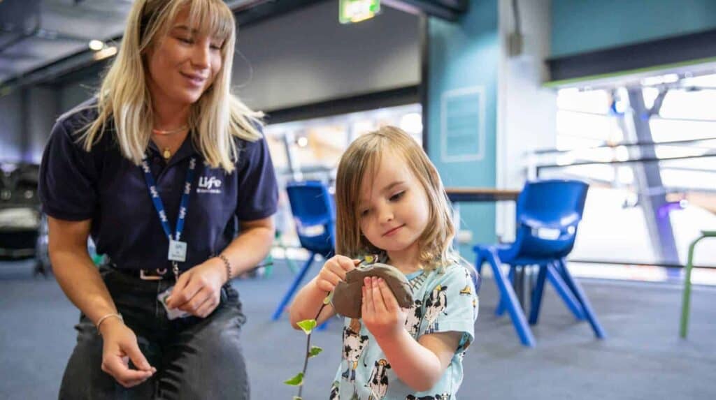 Young visitor enjoying clay leaf printing at pre-school day.