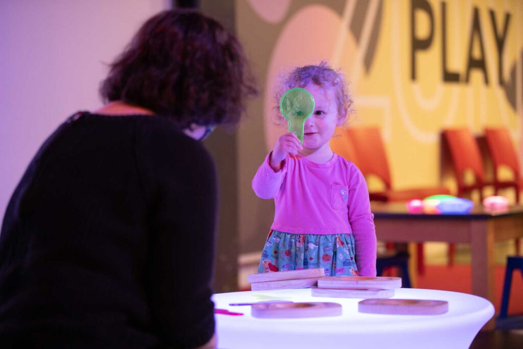 A younger visitor experimenting with light in Life Science Centre's Play Zone, a hands-on area for under-7s.