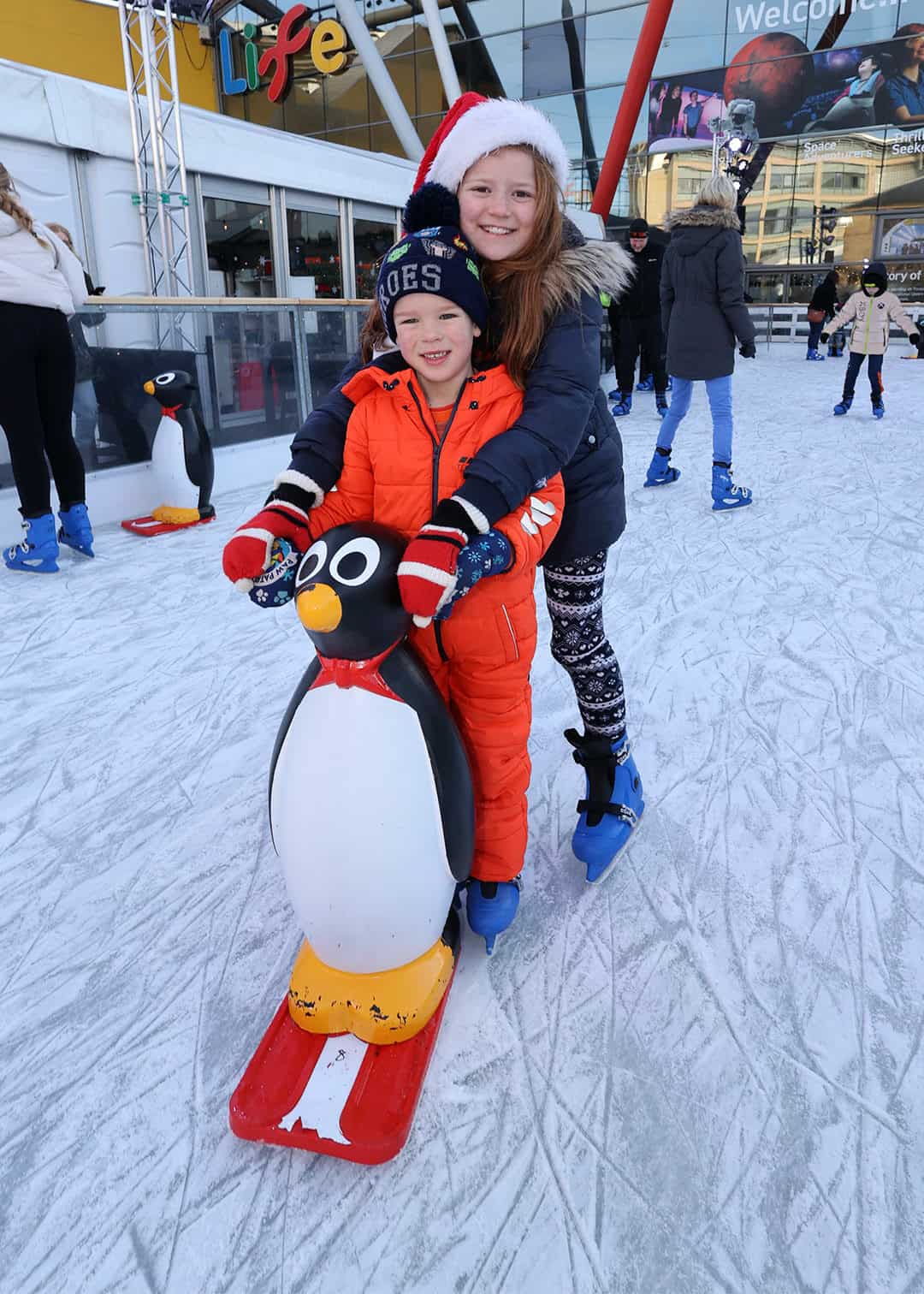 Brother and sister on Life's ice rink over the festive period with santa hats.