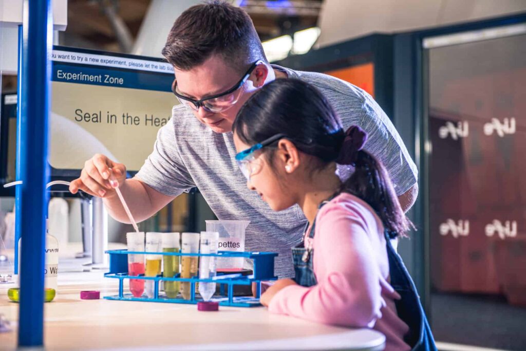 Boy and girl completing an experiment with a pipette in Life Science Centre's Experiment Zone.