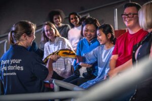 Explainer showing a soft toy snake to audience in Life Science Centre's theatre.