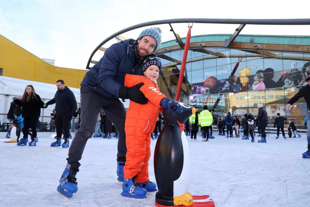Father and son in winter clothes having a skate on Life's open-air ice rink.