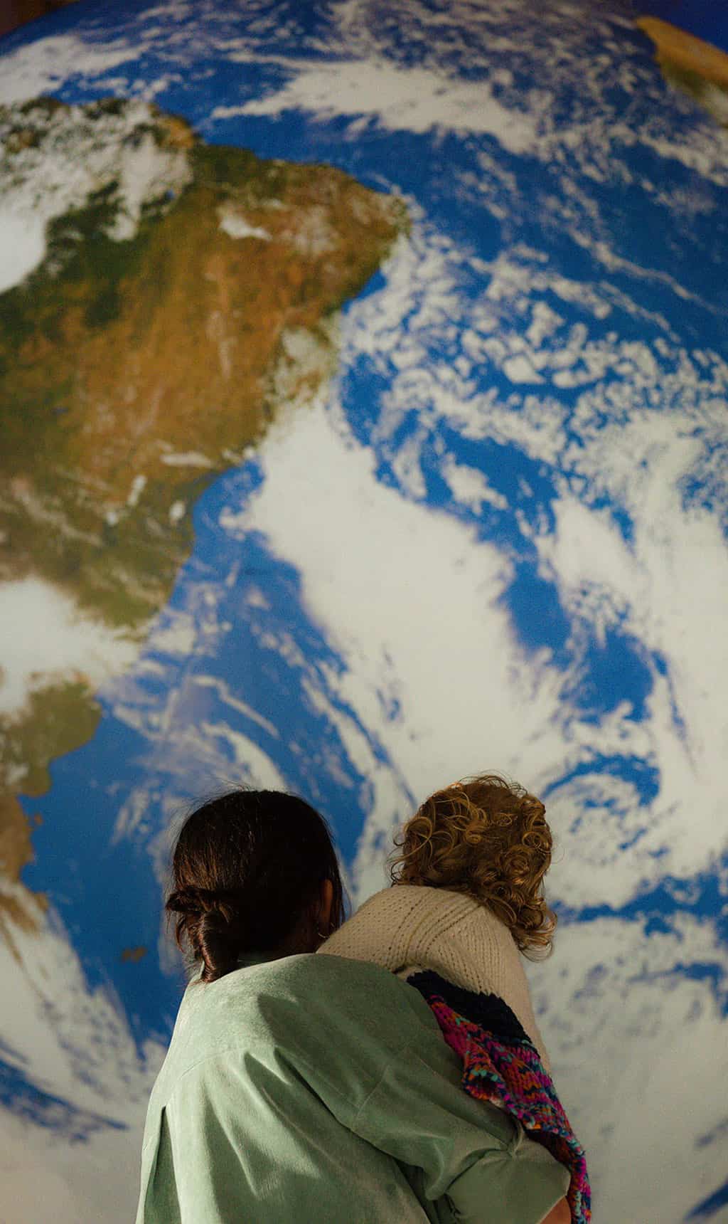 Mother And child stood looking up at Gaia, Life Science Centre's replica of planet Earth.