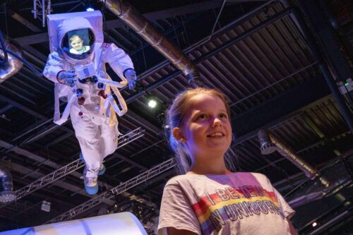 Girl Stood Underneath Astronaut Model With Her Face Projected Onto The Screen.
