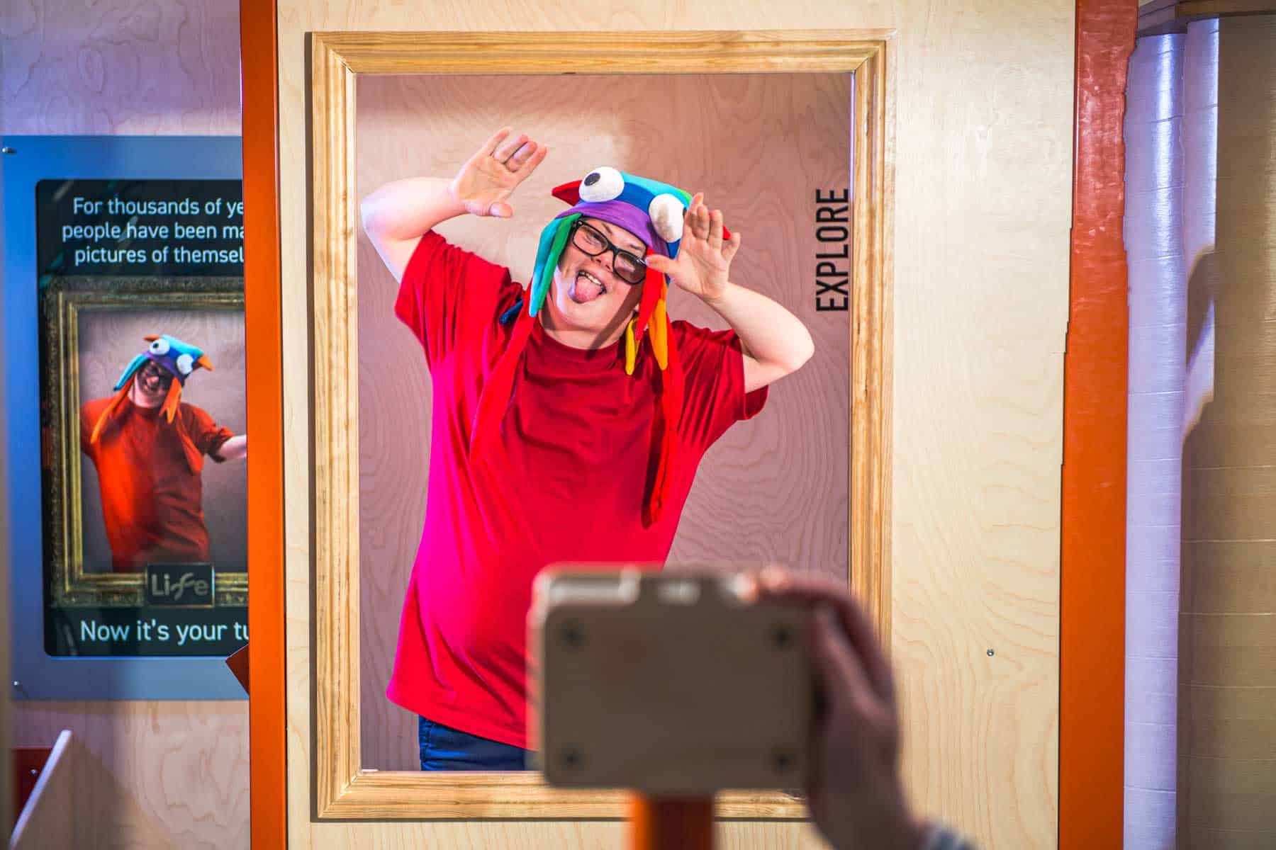 Life Science Centre visitor wearing a coloured hat and pulling a face in the photo booth.