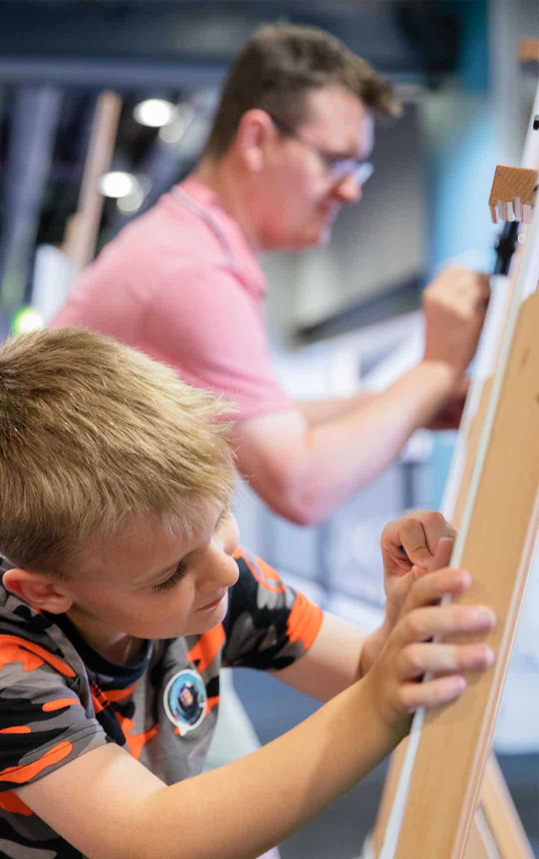 Father and son drawing pictures on the easels in Life's Hello World area.