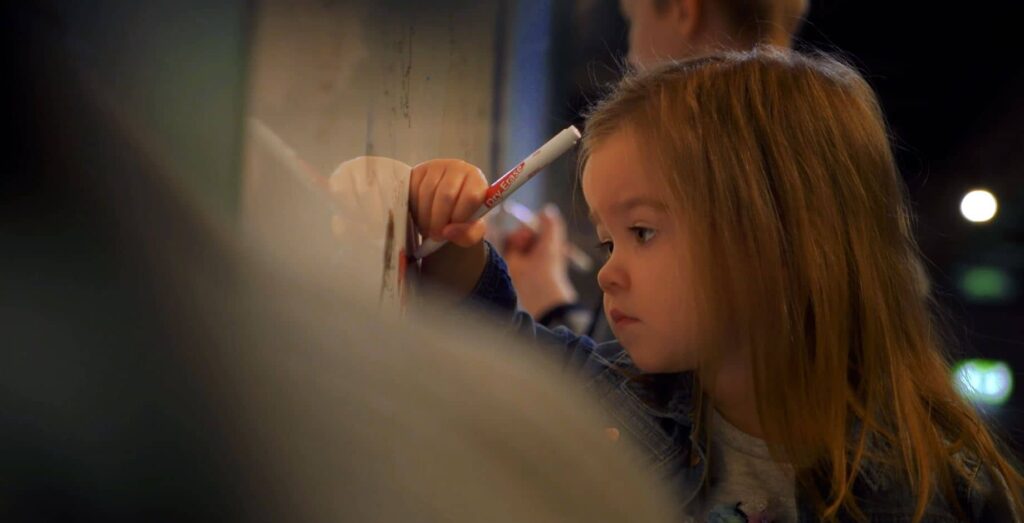 Little girl drawing on picture wall in Life Science Centre's Hello World Exhibit.