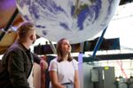 two-visitors-sat-underneath-Gaia-a-large-replica-of-Earth-at-the-entrance-of-the-science-centre