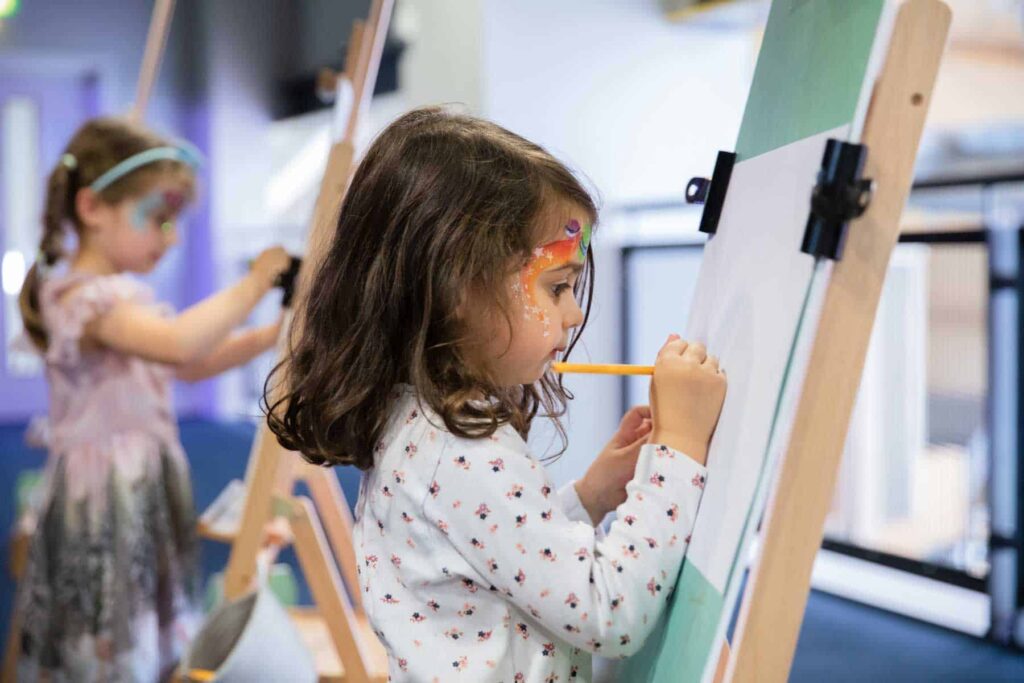 Young Girl Using Easel In Hello World.