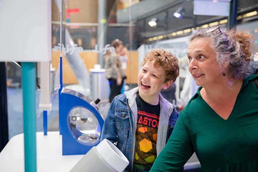 Life members looking through a microscope in Experiment Zone.