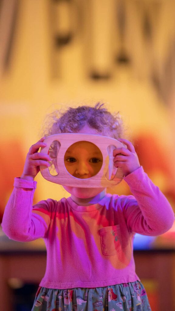 Little girl looking through coloured glass