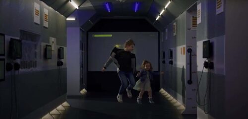 Two young children jumping in air in Life Science Centre's International Space Station model.