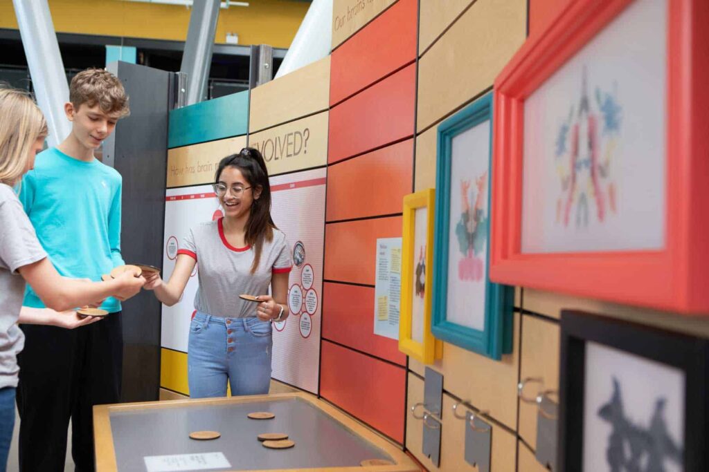 Teens Playing With Disk Exhibit In Brain Zone.