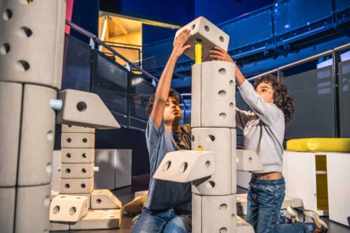 Two boys working together to assemble a rocket using large bricks in Life Science Centre's Space Zone.