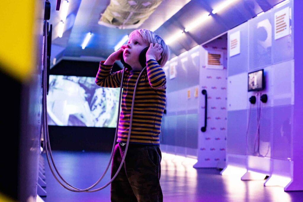 Young boy listening to an exhibit about an astronaut in Life Science Centre's Space Zone.