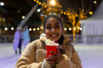 Young girl wearing reindeer antlers enjoying a festive hot chocolate on Life Science Centre's ice rink located in Newcastle.
