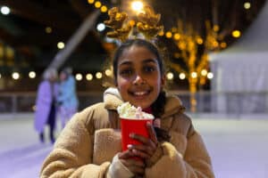 Young girl wearing reindeer antlers enjoying a festive hot chocolate on Life Science Centre's ice rink located in Newcastle.