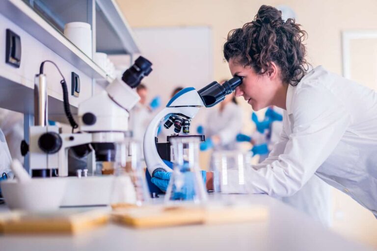 Students looking through a microscope in schools' workshop.