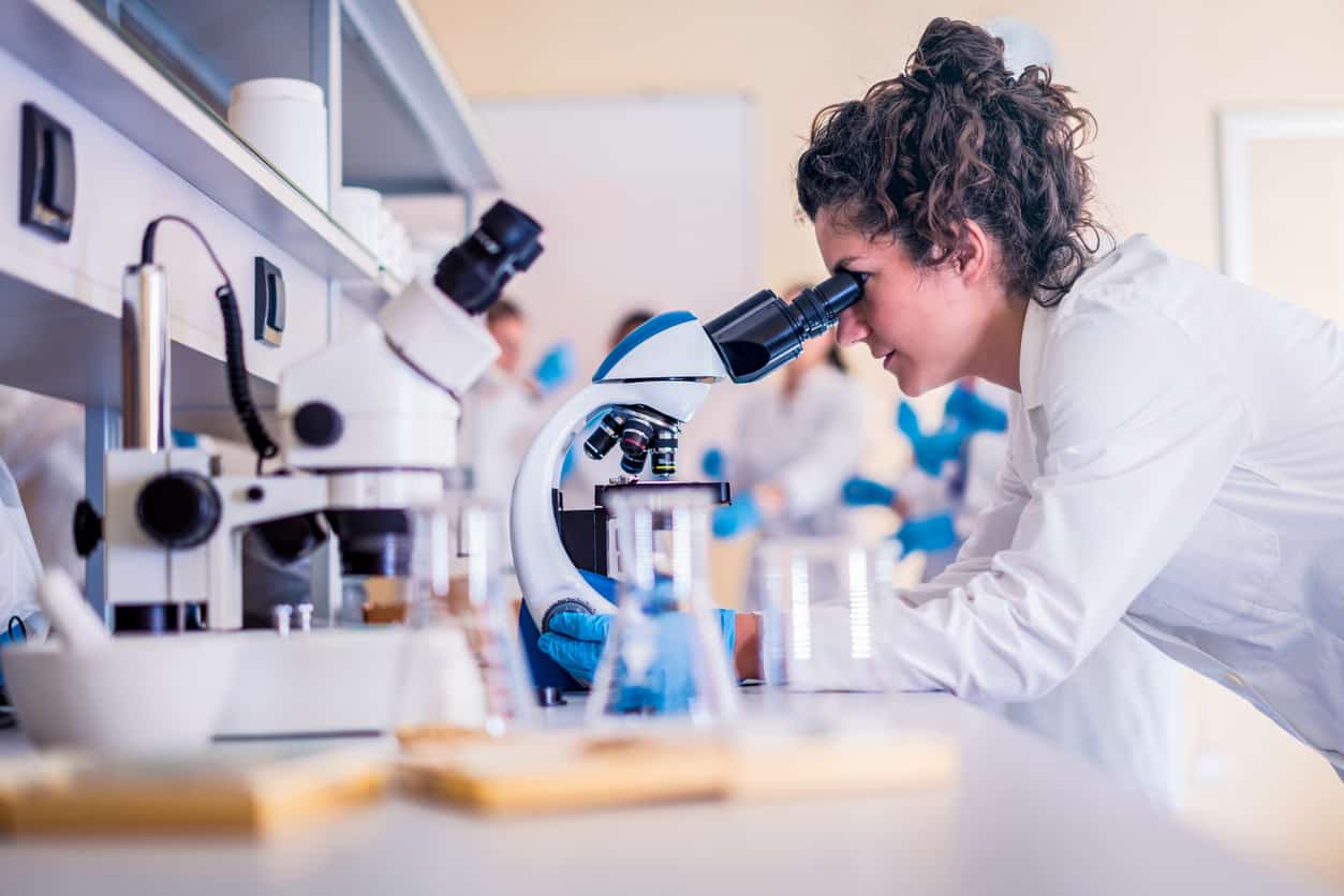 Students looking through a microscope in schools' workshop.