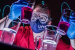 Explainer looking closely at beakers of colured chemicals in Science Theatre
