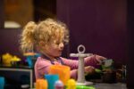 Little Girl In Toy Kitchen In Play Zone