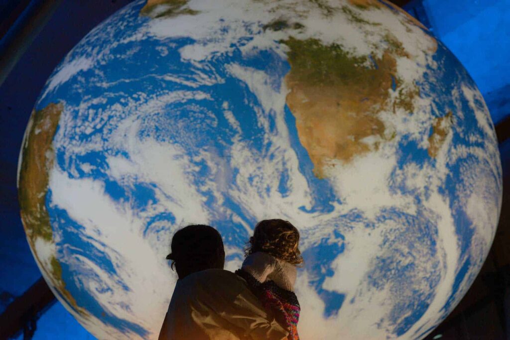 Mother And child stood looking up at Gaia, Life Science Centre's replica of planet Earth.