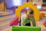 Toddler climbing in soft play area inside science centre.