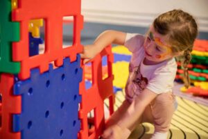 Young girl building with brightly coloured blocks in Life Science Centre's Play Zone.