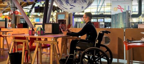 Man in wheelchair taking part in craft making activity inside Life Science Centre.