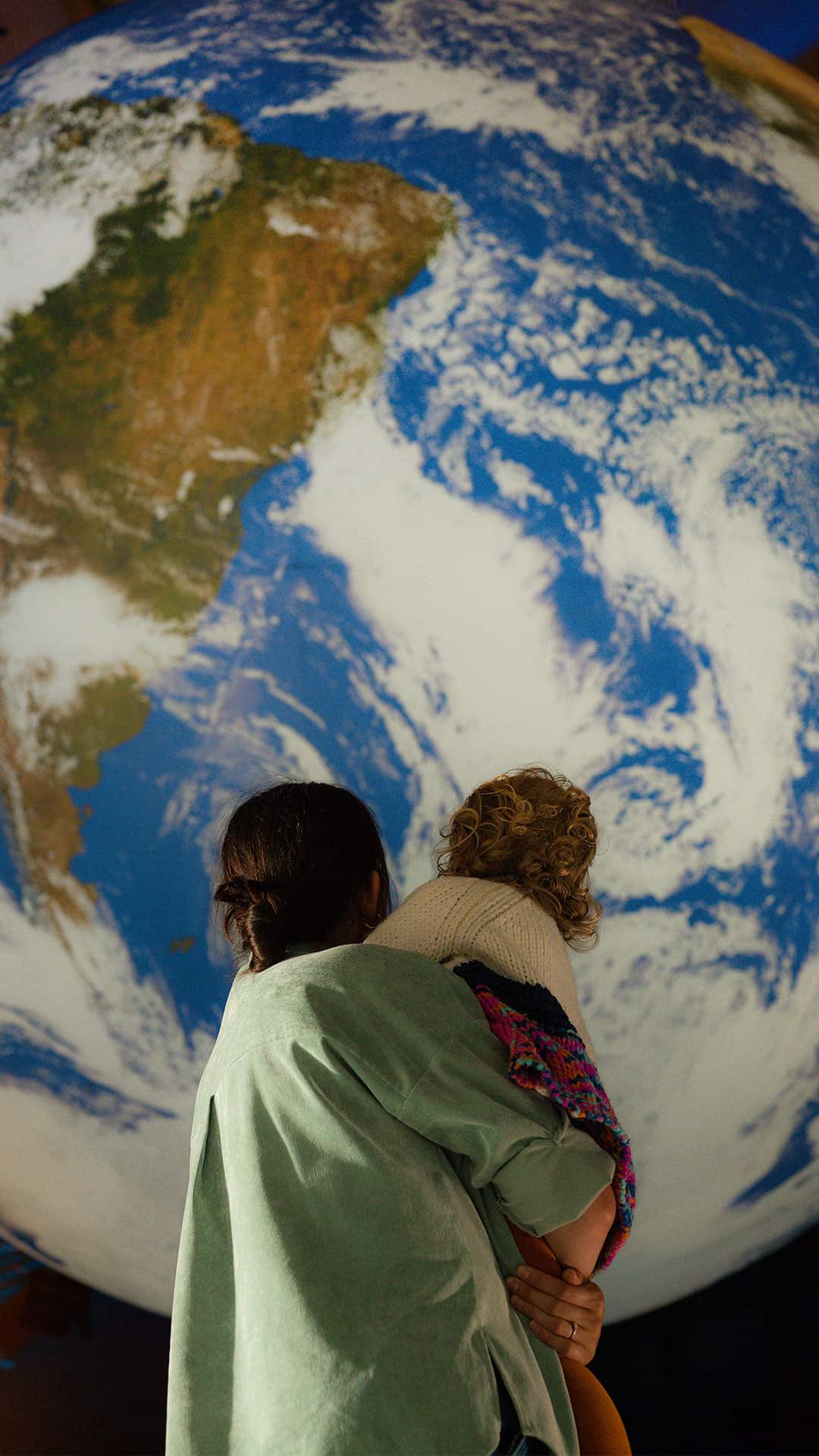 Mother And child stood looking up at Gaia, Life Science Centre's replica of planet Earth.